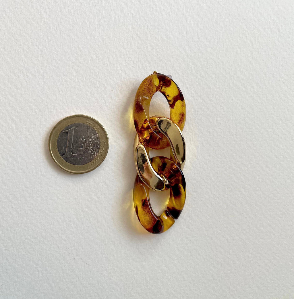 A tortoiseshell link brooch with gold-toned metal accents, shown next to a 1 Euro coin for scale on a white textured background.