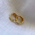 A pair of gold-toned 18K gold plated textured earrings with a crinkled wavy, ridged edge design, resting on a white linen fabric background.

keywords : 
waterproof earrings

skin friendly earrings

sea water friendly earrings

round_hoops

modern_hoops

modern_gold_hoops

hoops

hoop_earrings

golden_hoops

gold_hoops

gold plated hoops

cute_hoops

crinkled hoops

contemporary_hoops

circular_hoops

brass_hoops

brass_hoop_earr

