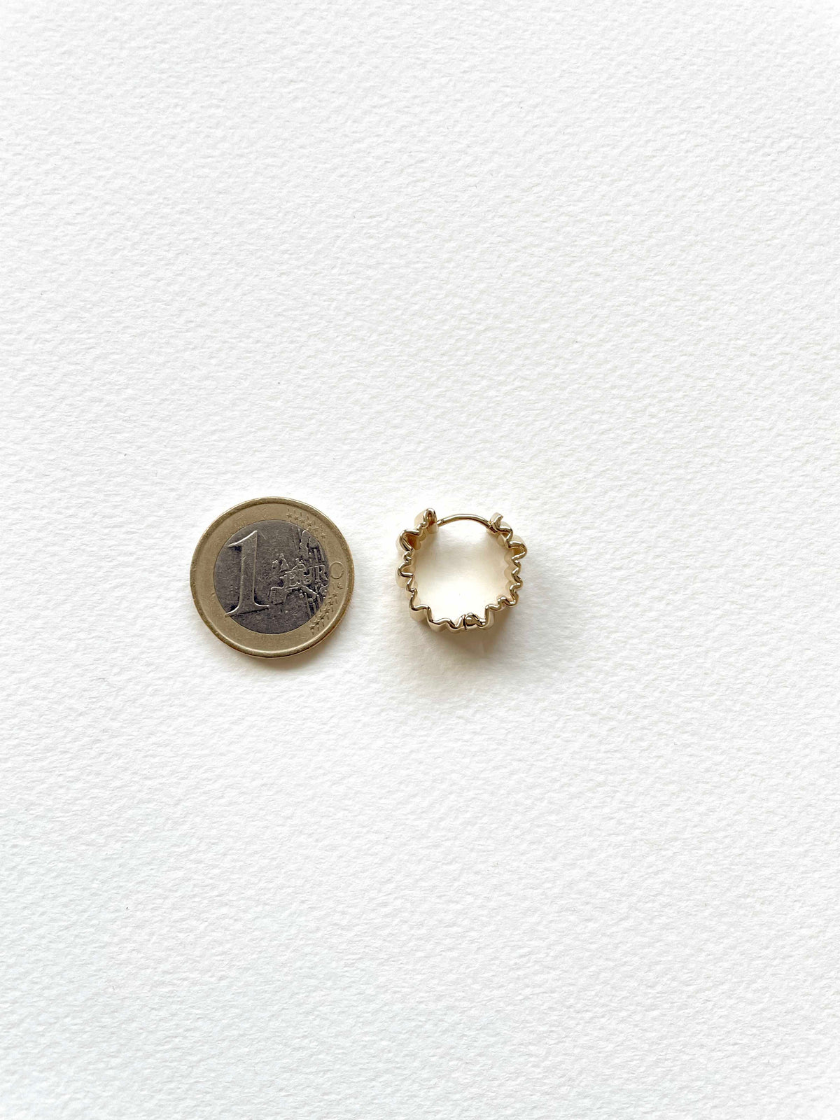 A small 18K gold plated huggie hoop earring with crinkled design shown next to a 1 Euro coin for scale, on a textured white background.

waterproof earrings

skin friendly earrings

sea water friendly earrings

round_hoops

modern_hoops

modern_gold_hoops

hoops

hoop_earrings

golden_hoops

gold_hoops

gold plated hoops

cute_hoops

crinkled hoops

contemporary_hoops

circular_hoops

brass_hoops

brass_hoop_earrings

