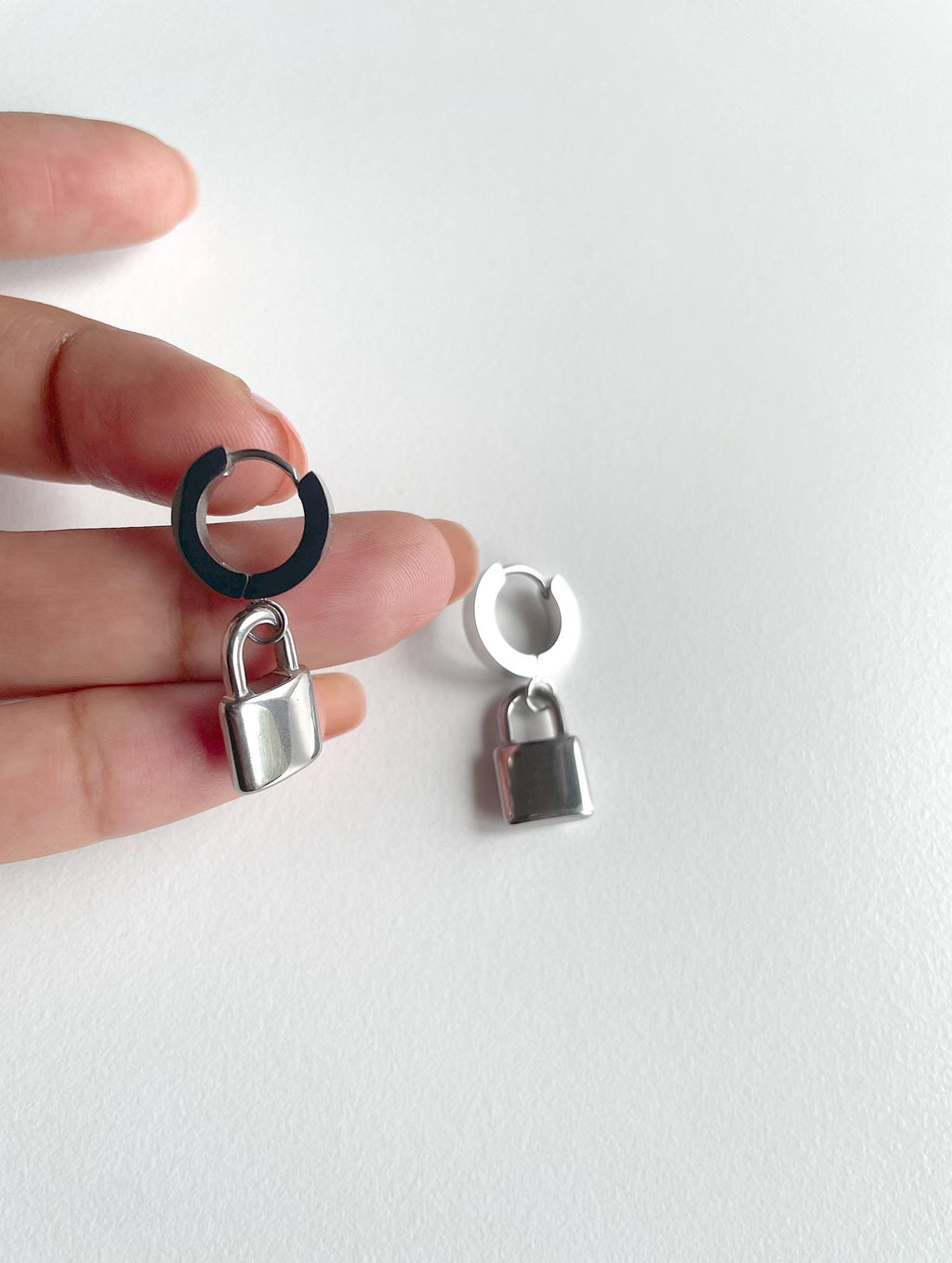 silver padlock earrings, huge hoops on human hand for scale