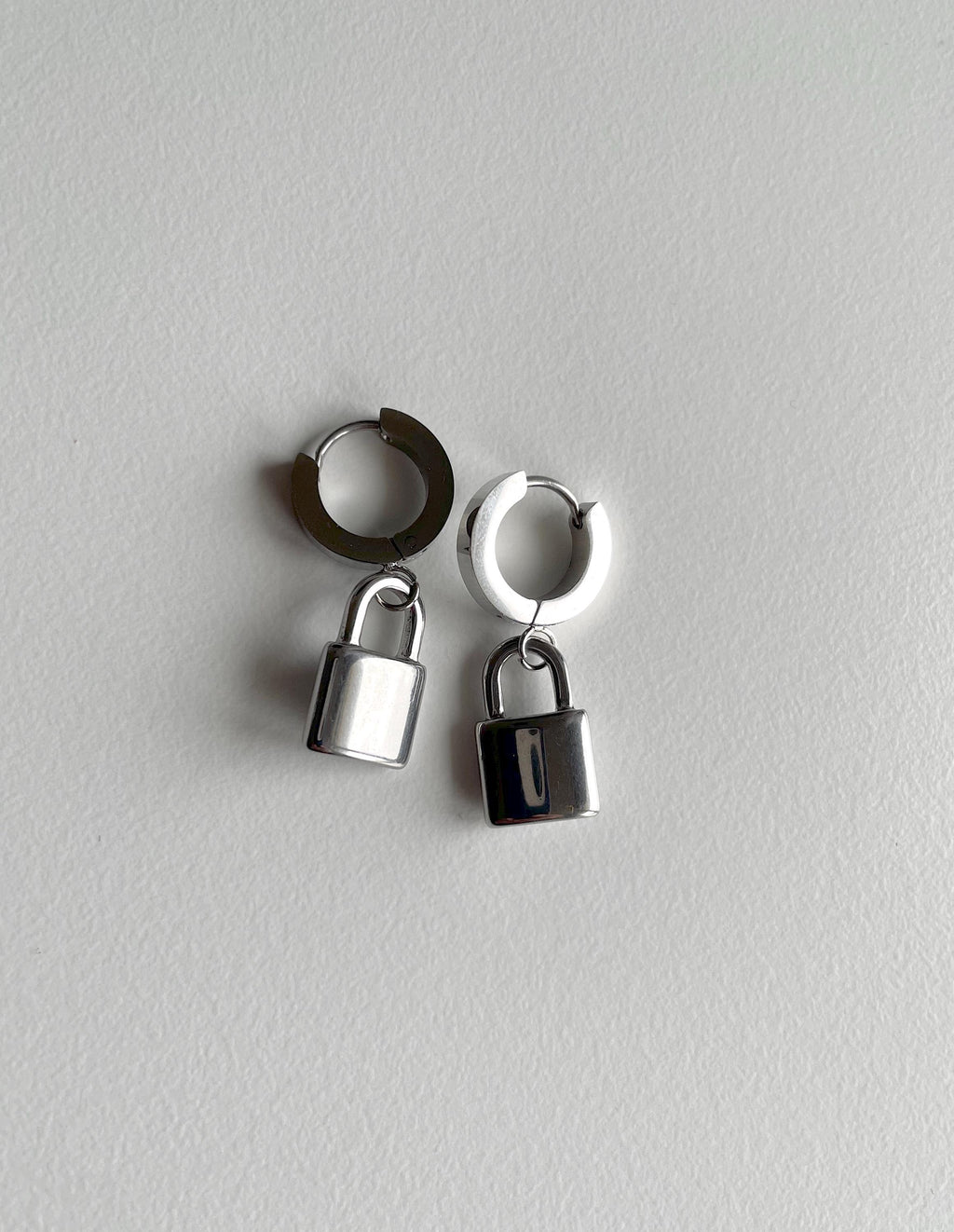A pair of silver padlock earrings on white background