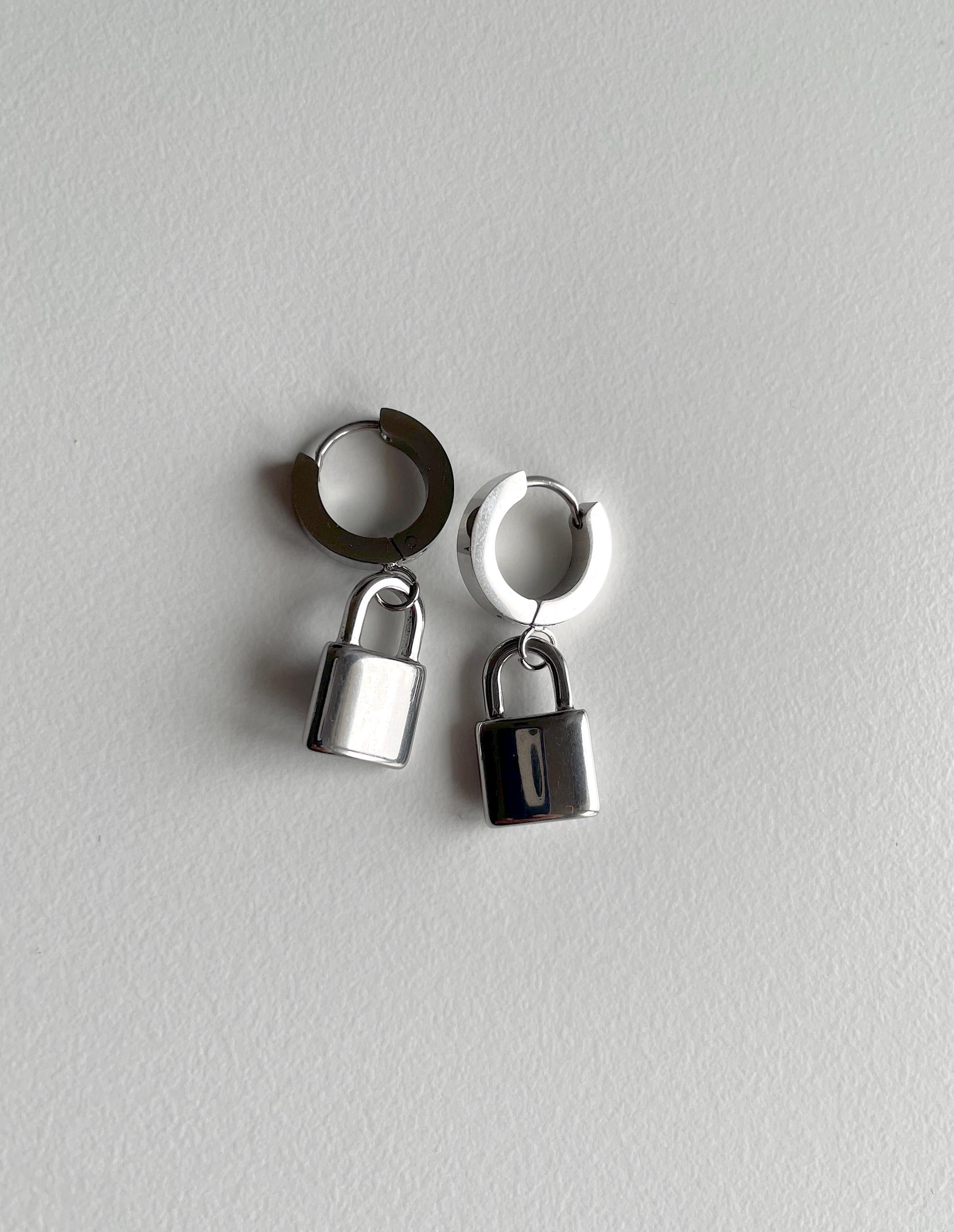 A pair of silver padlock earrings on white background