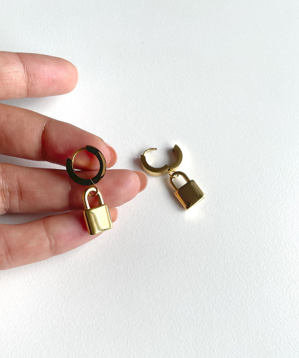 gold padlock earrings, huge hoops on human hand for scale