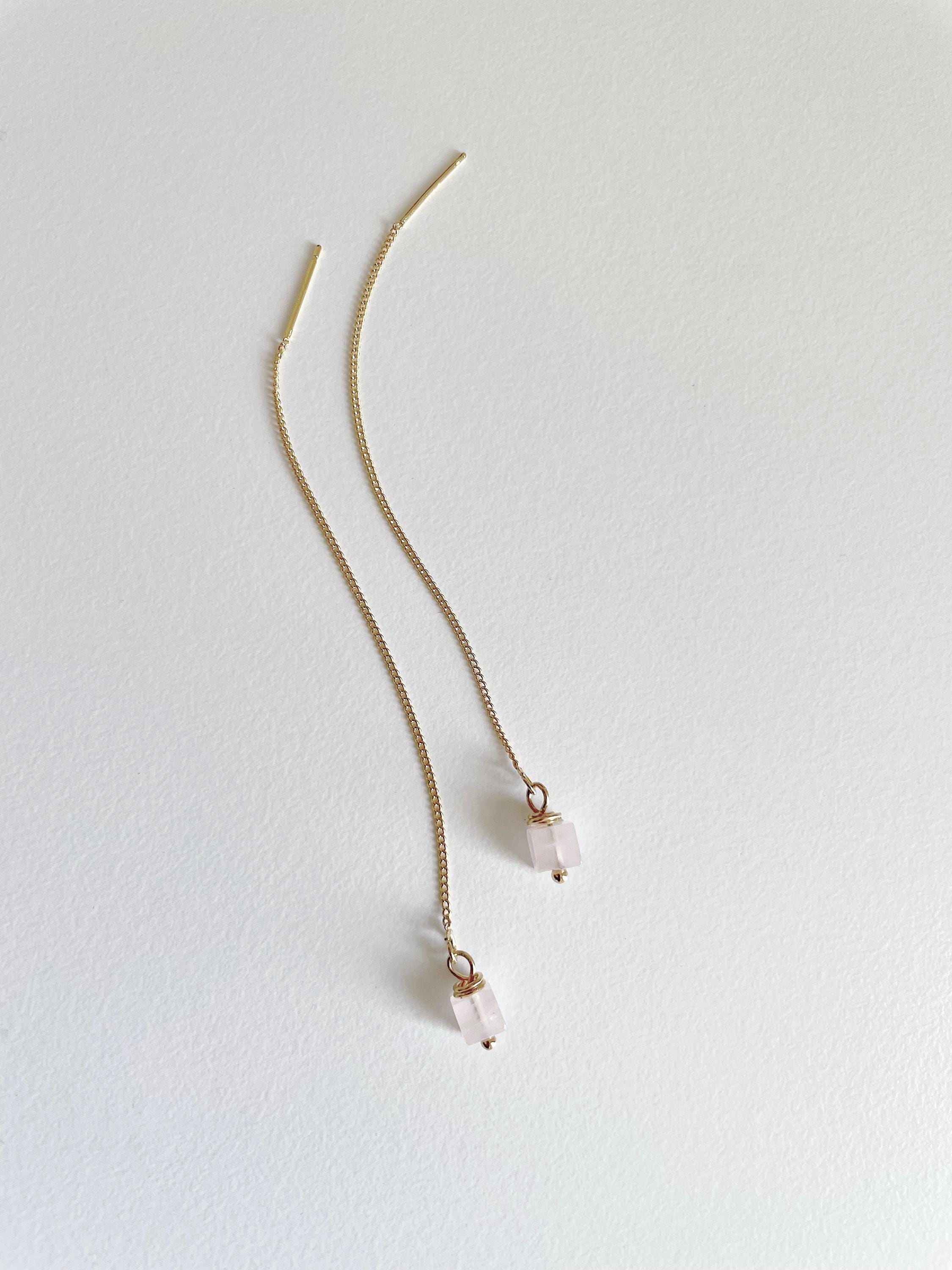 A pair of delicate gold chain earrings with small pale pink bead drops, displayed on a clean white background.