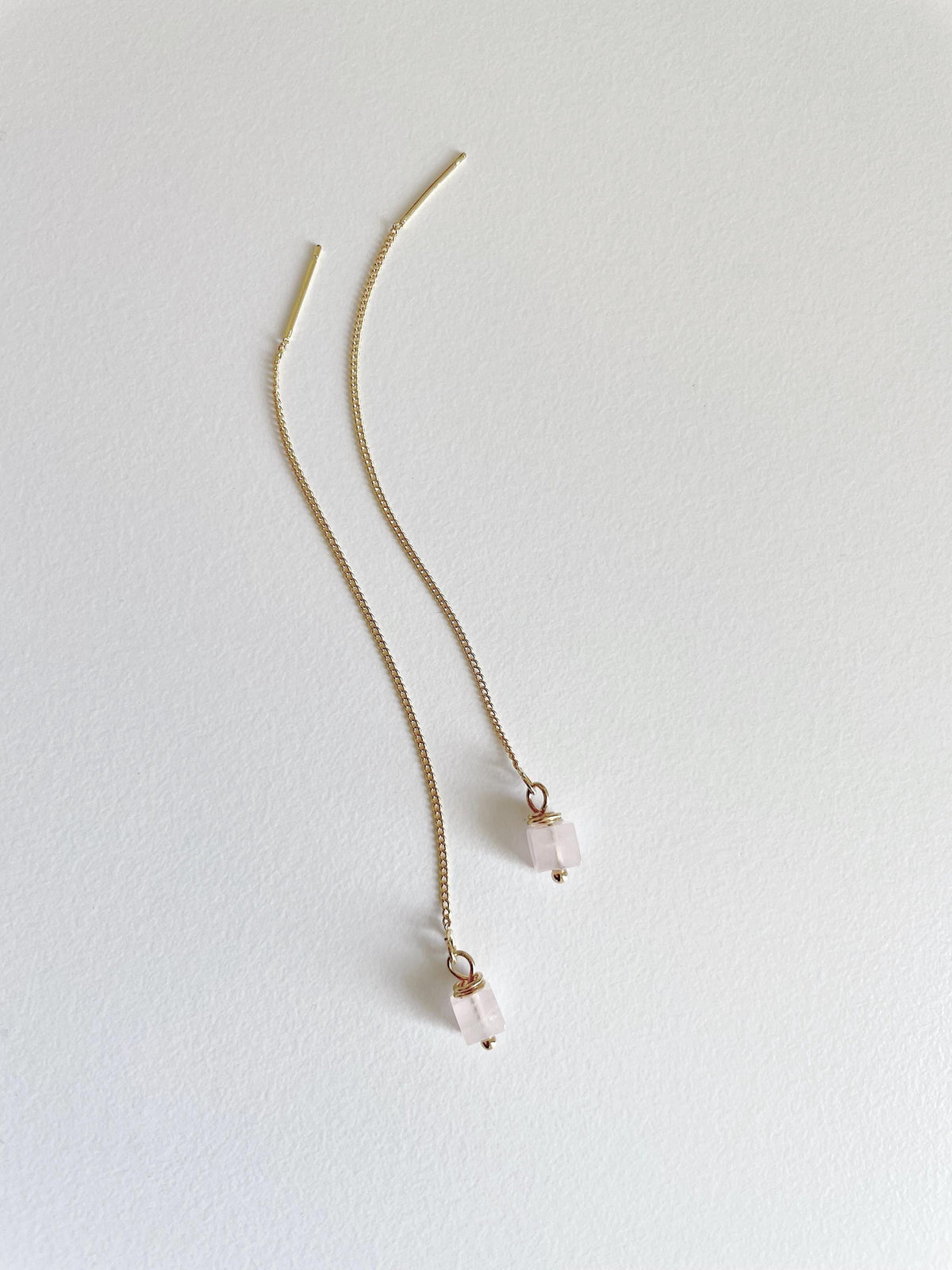 A pair of delicate gold chain threader earrings with small square pale pink rose quartz bead drops, displayed on a clean white background.