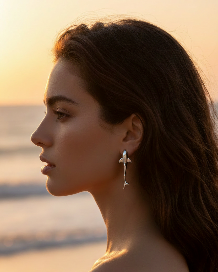 Model wearing tiny silver shark earrings on beach